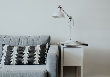 A lamp sitting on a table beside a blue couch.