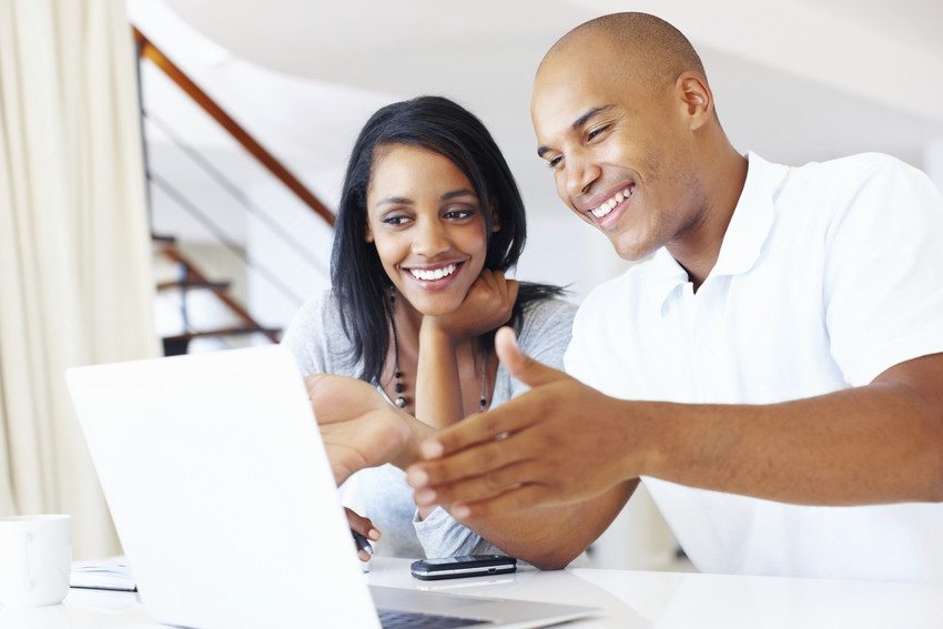 A man and woman looking at a computer and smiling.