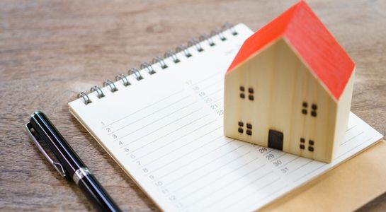 A house on a pad of paper with a pen nearby.