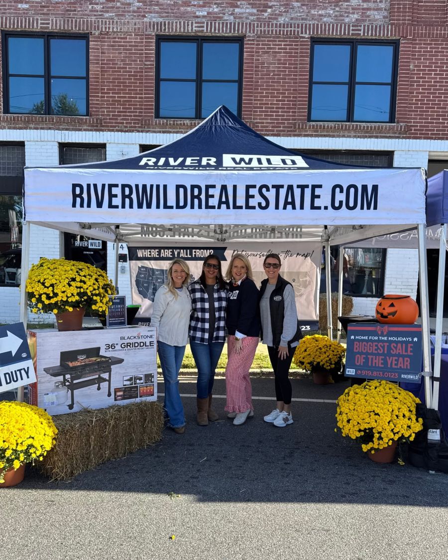 RiverWILD booth with team members, yellow mums, a pumpkin, and the Blackstone Grill giveaway display