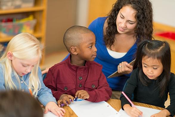 Small children writing with teacher