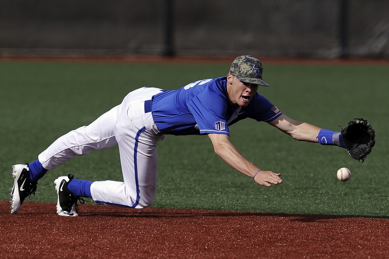 Man in a baseball uniform sliding onto a plate to catch a ball.