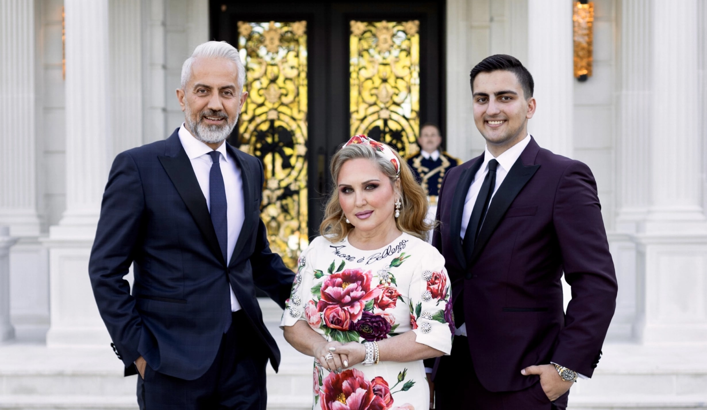 Two men in tuxedos and a woman in a flowered dress standing between them