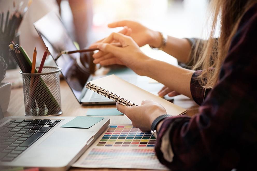 Women taking notes by a computer