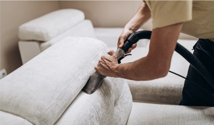 A man vacuuming the couch