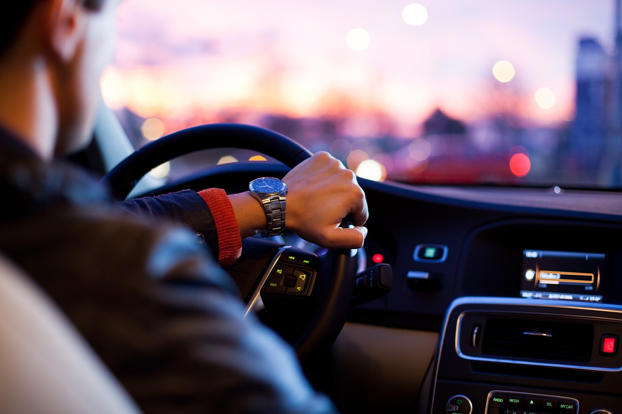 Man driving in a car at twilight.