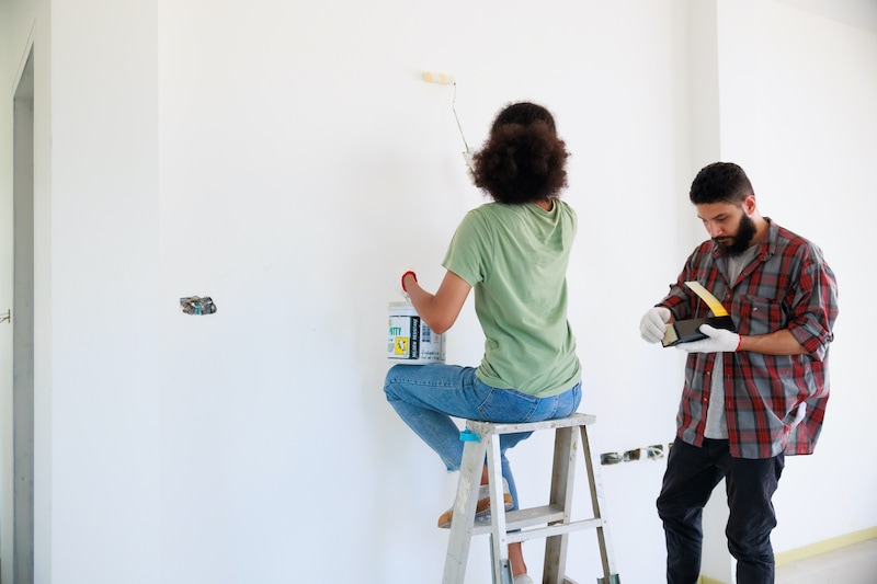 A woman and man painting a wall